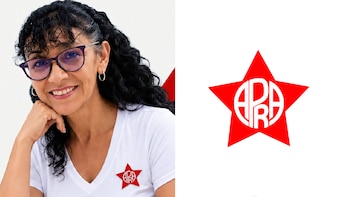 Una mujer con anteojos sonríe junto al emblema del Partido Aprista Peruano, consistente en una estrella roja con letras blancas