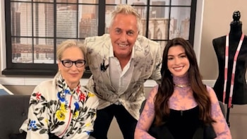 Meryl Streep con lentes y blusa blanca floral, Anne Hathaway con top morado de encaje y Marley con un traje blanco estampado posan sonriendo