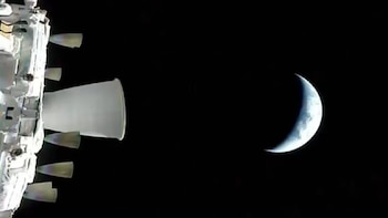 Foto aérea mostrando um módulo de nave espacial branco com vários propulsores à esquerda e a Terra na Lua à direita