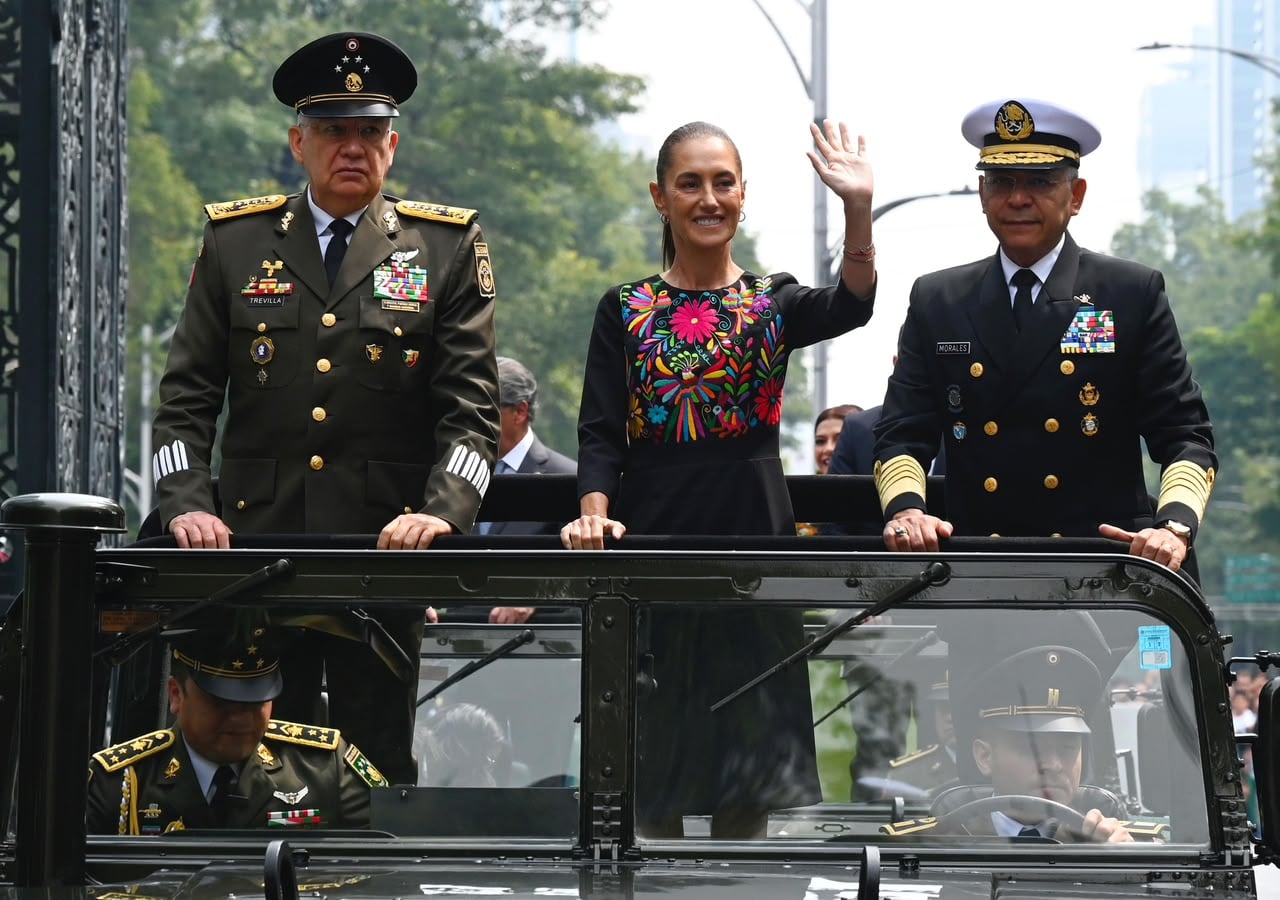 Claudia Sheinbaum saluda desde un vehículo abierto junto a los mandos de las Fuerzas Armadas de México durante una ceremonia oficial.
