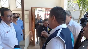 Luis Dyer escucha a Patrich Jordan Pantoja en la entrada de un centro de salud junto a personal médico y periodistas