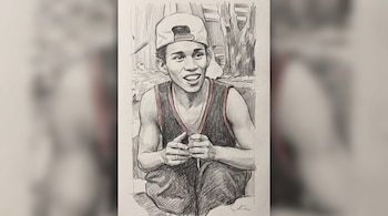 Dibujo a lápiz grafito de un joven sonriendo, sentado en cuclillas, con gorra clara, musculosa oscura con ribetes rojos, cadena y manos unidas. Fondo.