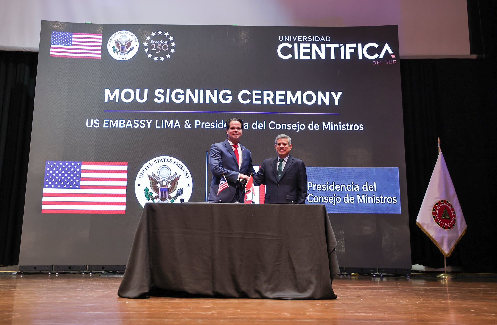 Luis Galarreta y Bernie Navarro estrechan sus manos tras la firma de un memorando de entendimiento para la cooperación en inteligencia artificial entre Perú y Estados Unidos.