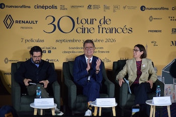 Tres personas sentadas en sillones ante un mural amarillo publicitario del Tour de Cine Francés con pequeñas mesas de centro enfrente