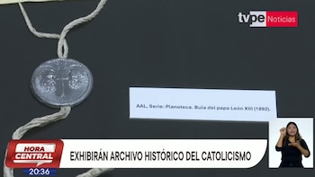 Un sello de metal sujeto con una cuerda junto a una cartela informativa y una franja de un noticiero de televisión