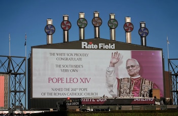 Marcador del Rate Field con imagen del Papa León XIV saludando y mensaje de los White Sox. Varias estructuras con molinetes decorativos visibles arriba contra cielo azul