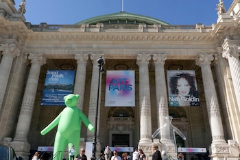 Fachada del Grand Palais con columnas, pancartas y dos grandes esculturas inflables, una verde y una transparente, bajo un cielo azul despejado