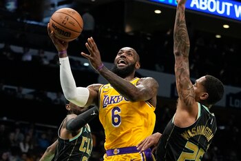 El alero de los Lakers de Los Ángeles LeBron James lanza el balón entre los delanteros Jalen McDaniels y P.J. Washington de los Hornets de Charlotte en el encuentro del lunes 2 de enero del 2023. (AP Foto/Chris Carlson)