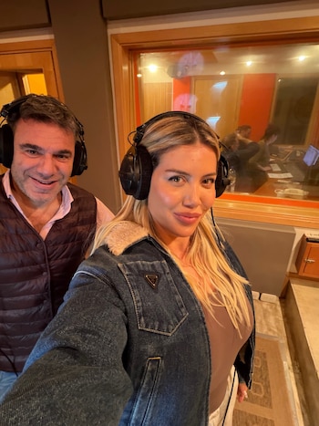 Wanda Nara en primer plano y un hombre detrás, ambos con auriculares grandes en un estudio de grabación