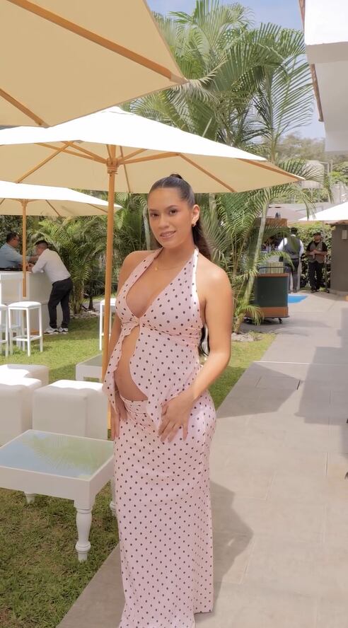 Gianella Marquina, hija mayor de Melissa Klug, asiste al baby shower de su primera hija Tezza, posando en un jardín con sombrillas y mobiliario blanco.