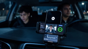 Teléfono inteligente en un soporte de automóvil que muestra la interfaz de Uber con video en directo, un mapa de ruta y el rostro del conductor