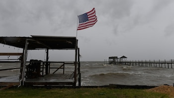 Una bandera estadounidense ondea al viento generado por los efectos de Isaías en una playa desierta el viernes 9 de octubre de 2026, en Mon Louis Island, Alabama. (Foto AP/Octavio Jones)