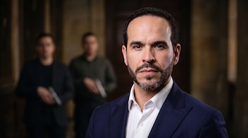 Abelardo de la Espriella en primer plano con traje azul; al fondo, dos personas desenfocadas sostienen armas de fuego.