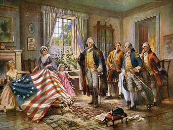 En una sala, una mujer y dos niñas muestran una bandera de Estados Unidos con trece estrellas. Cinco hombres con ropa colonial observan