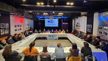 Grupo de personas sentadas en mesa con forma de U, con banner y proyección en pantalla con el logo 'MDF Movimiento Derecho al Futuro Ciudad de Buenos Aires'