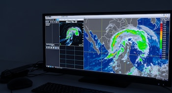 Pantalla de monitor con mapa de radar meteorológico que muestra la onda tropical 22 sobre México, con colores azul, verde, gris y blanco.