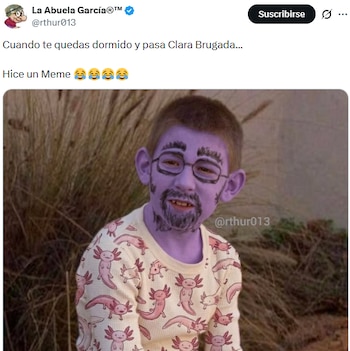 Un niño con la cara pintada de color morado y barba y gafas negras dibujadas, sonríe ligeramente. Viste una camiseta blanca estampada con ajolotes rosados. El fondo es un arbusto seco