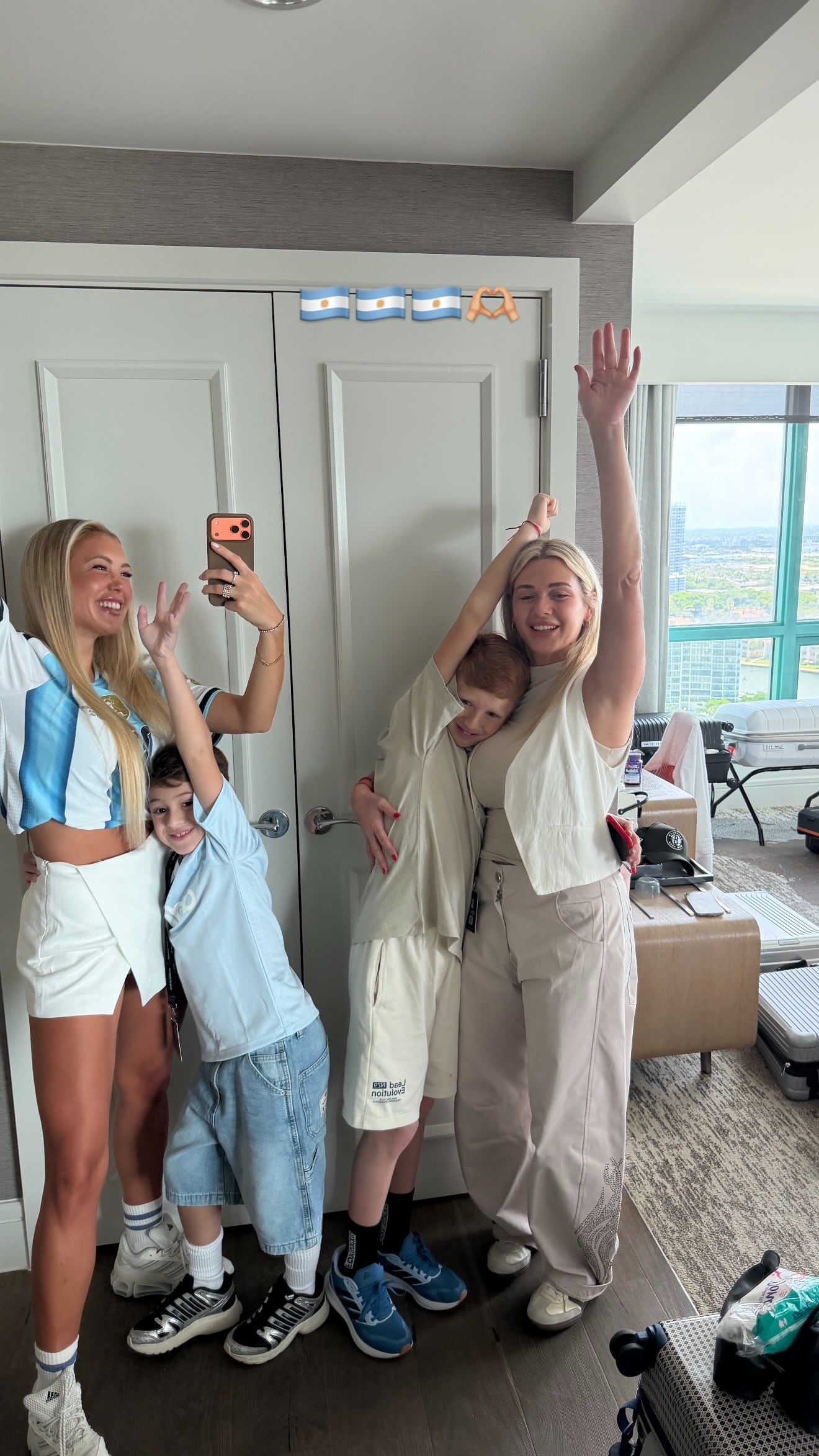 Ludmila Isabella, pareja de Nico González, posa con dos niños y otra mujer en una habitación, llevando indumentaria y con banderas que aluden a la selección argentina.