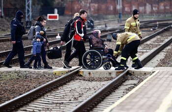 A family crosses the tracks to take the train, after fleeing from the Russian invasion of Ukraine, at the train station in Przemysl, Poland, March 3, 2022. REUTERS/Yara Nardi