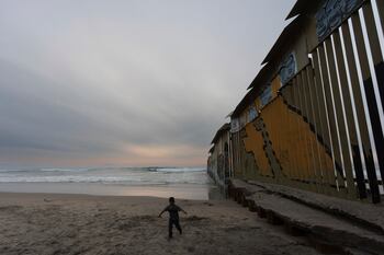 Niño caminando junto al muro fronterizo entre Estados Unidos y México en la costa del Pacífico
