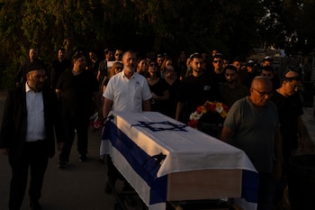 Varias personas trasladan el féretro,