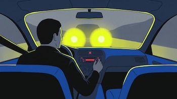 Interior de un auto de noche, conductor de espaldas ajusta la radio, otro vehículo se acerca de frente con las luces altas a través del parabrisas.
