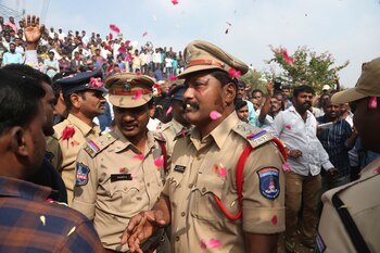 La gente arroja pétalos de flores a policías indios que custodian la zona en la que fue abatido un sospechoso de violación, en Shadnagar, a unos 50 kms (31 millas) de Hyderabad, India, el 6 de diciembre de 2019. (AP Foto/Mahesh Kumar A.)