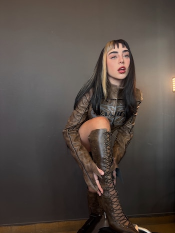 Nicki Nicole muestra su nuevo corte de cabello con flequillo recto y melena oscura mientras posa con los ojos entrecerrados y los labios pintados de rojo.
