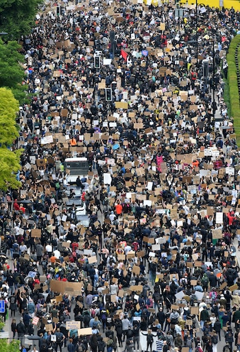 Protesters hold placards as they attend a demonstration outside the US Embassy in London on June 7, 2020, organised to show solidarity with the Black Lives Matter movement in the wake of the killing of George Floyd, an unarmed black man who died after a police officer knelt on his neck in Minneapolis. - Taking a knee, banging drums and ignoring social distancing measures, outraged protesters from Sydney to London on Saturday kicked off a weekend of global rallies against racism and police brutality. (Photo by JUSTIN TALLIS / AFP)