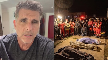 Actor Christian Meier con camiseta gris y a su lado rescatistas de emergencia en uniformes junto a tres cuerpos cubiertos en el suelo durante la noche.