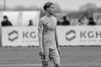 Fotografía en blanco y negro de un joven futbolista con uniforme deportivo en un campo de juego