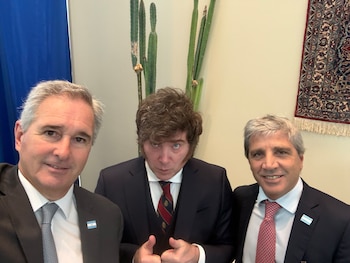 Tres hombres en traje y corbata se toman una selfie. En el fondo se observa una pared clara, un cactus y un tapiz decorativo
