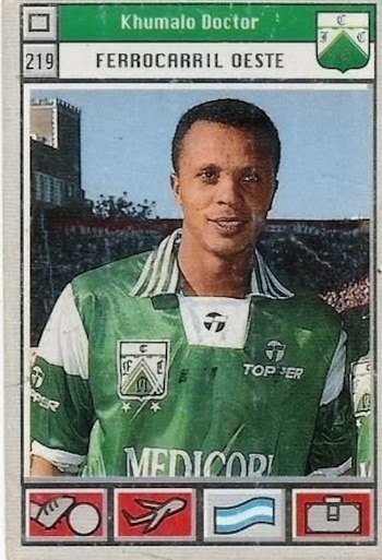 Tarjeta coleccionable vintage de Doctor Khumalo, futbolista de piel oscura, sonriendo con camiseta verde y blanca de Ferrocarril Oeste, fondo de estadio