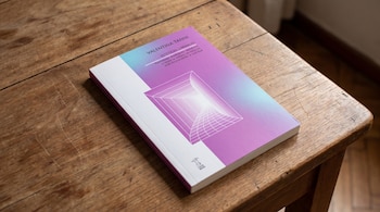 Un libro titulado Estéticas Liminales de Valentina Tanni, con una portada de colores degradados de azul a morado y un gráfico de túnel, está sobre una mesa de madera.