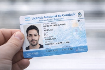 Mano sosteniendo Licencia Nacional de Conducir de Argentina con foto, nombre, DNI, fecha de nacimiento, domicilio, fechas de emisión y vencimiento.