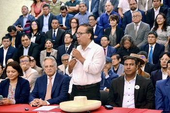 Roberto Sánchez, un hombre con gafas y camisa blanca, habla a un micrófono rodeado de personas en un evento político