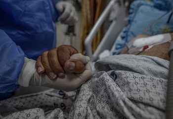 Imagen de archivo de un sanitario que agarra la mano de un paciente del hospital Al-Nasser, al sur de la Franja de Gaza. EFE/Mohammed Saber