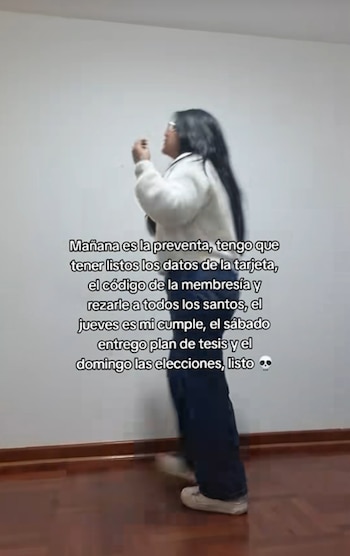 Una persona con cabello oscuro, suéter blanco y pantalones oscuros, de pie frente a una pared blanca y piso de madera. Texto blanco superpuesto