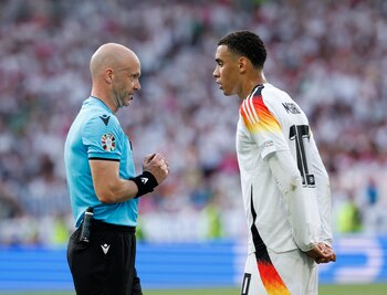 El árbitro Anthony Taylor escucha