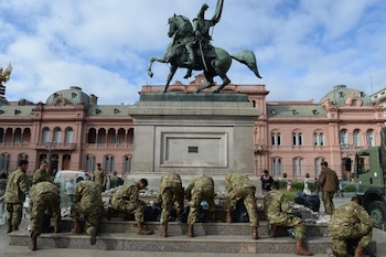 Efectivos militares en uniforme camuflado colocan piedras en la base de un monumento ecuestre frente a la Casa Rosada en Plaza de Mayo
