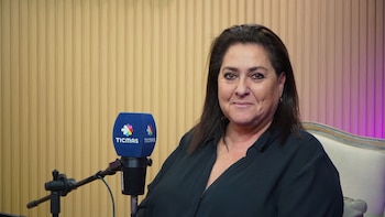 Una mujer de cabello oscuro y camisa negra está frente a un micrófono azul con la marca Ticmas sobre un fondo de madera