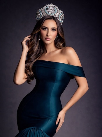 Retrato de Abril Duhalde, Miss Universo CABA, con cabello castaño ondulado, una corona plateada con gemas y un vestido verde oscuro sin hombros