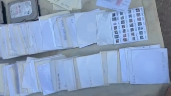 Filas de fundas de papel blanco para discos compactos junto a dos discos duros de computadora sobre una superficie clara