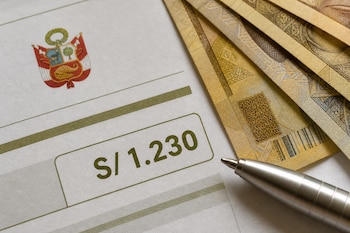 Documento impreso con el escudo de Perú y el texto S/ 1.230, junto a varios billetes en moneda nacional y un bolígrafo metálico.