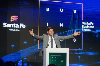 Un hombre con traje gris habla tras un podio blanco ante una pantalla gigante con la inscripción Santa Fe Business Forum