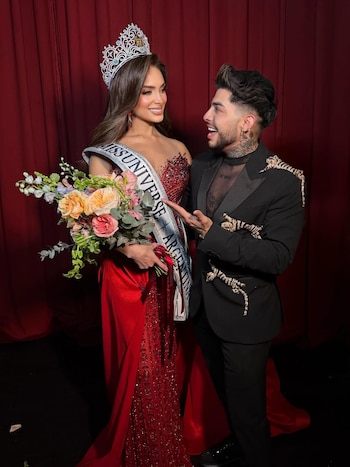 Tamara Rogouski, con corona, vestido rojo brillante y banda de Miss Universo Argentina, junto a Jorge Ramírez, con traje negro y tatuajes, sobre un fondo rojo