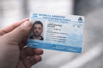 Una mano sostiene una licencia nacional de conducir de Argentina con una foto de un hombre, su nombre Emiliano Lopez Martinez y sus datos personales.