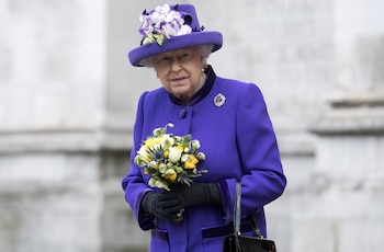 Abrigo y sombrero púrpura intenso con flores textiles blancas y violetas, broche de gema violeta y guantes negros para un evento oficial (AFP)