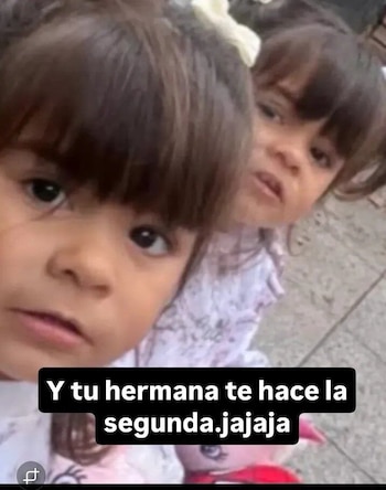 Primer plano de dos niñas pequeñas de pelo oscuro, una adelante mirando la cámara y la otra detrás, con la frase "Y tu hermana te hace la segunda. jajaja"