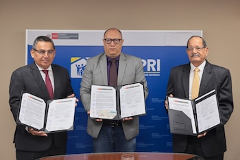 Tres hombres en traje y corbata sostienen documentos abiertos en una ceremonia de firma, con un banner azul del Ministerio de Vivienda y COFOPRI de fondo